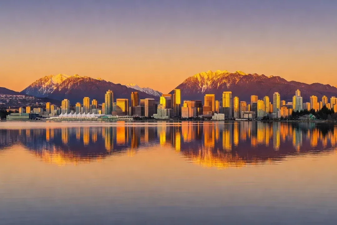 Vue de Vancouver avec les montagnes enneigées reflétées dans l'eau, Colombie-Britannique, coucher de soleil